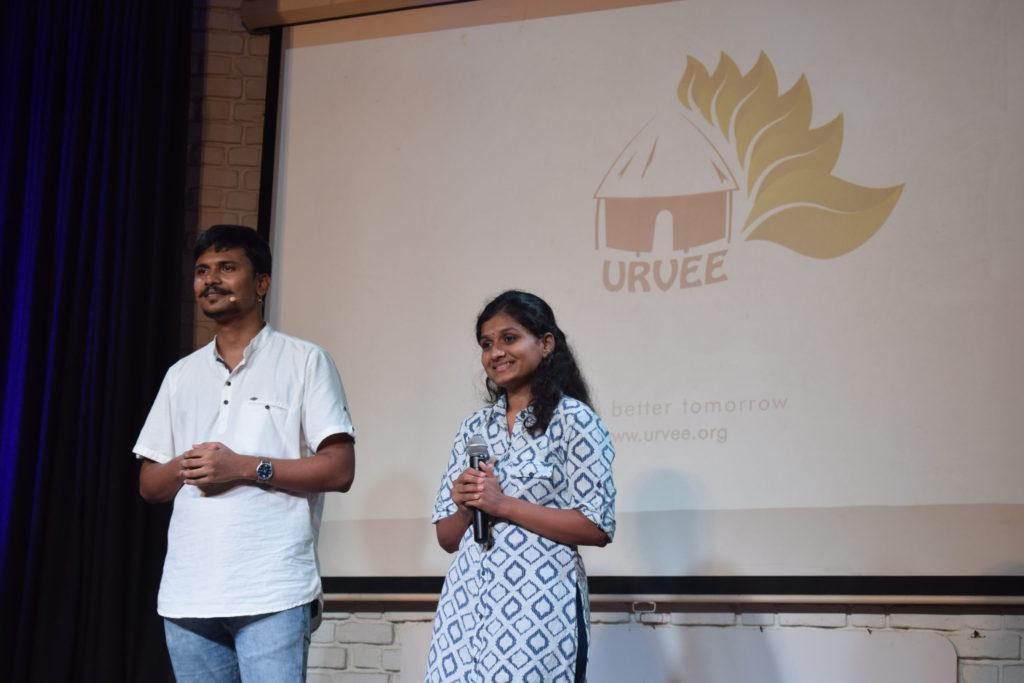 prasad & amrutha on stage; urvee logo in the background
